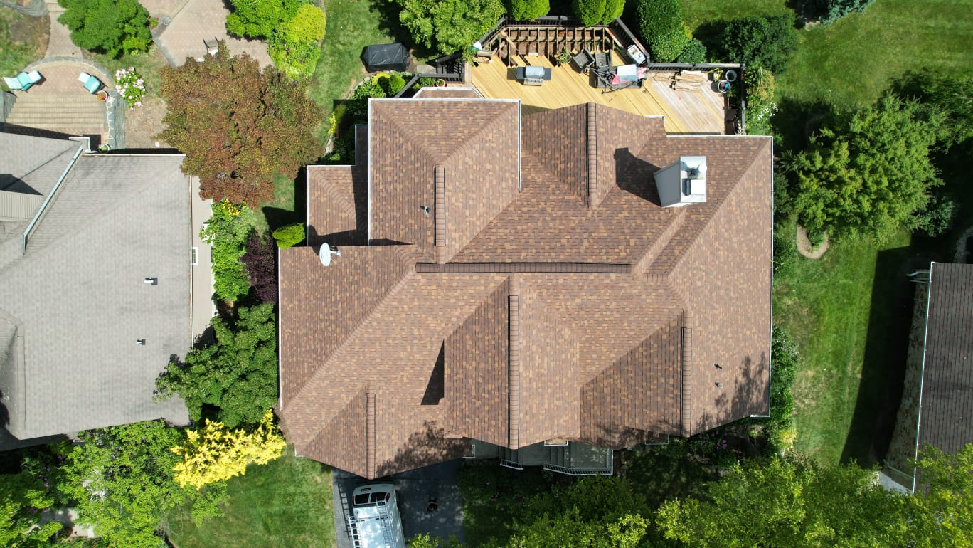 Aerial view of a residential shingle roof surrounded by trees in New Jersey